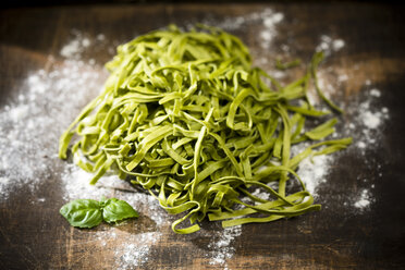 Frische Tagliatelle Spinaci, Basilikumblätter und Mehl auf dem Holztisch - MAEF008106