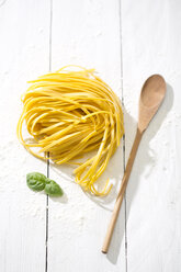 Tagliolini classico, leaves of basil, wooden spoon and flour on white wooden table - MAEF008079