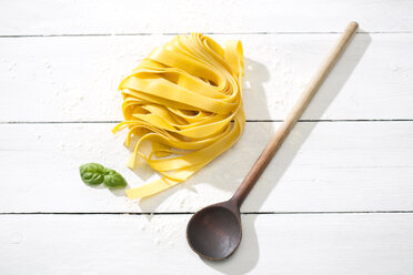 Fresh Pappardelle classico, leaves of basil, wooden spoon and flour on white wooden table - MAEF008080