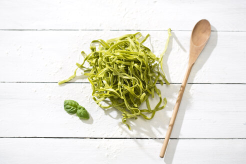 Frische Tagliatelle Spinaci, Basilikumblätter, Holzlöffel und Mehl auf weißem Holztisch - MAEF008082