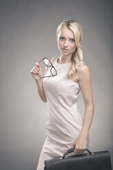 Portrait of a young businesswoman holding glasses and briefcase - VTF000137