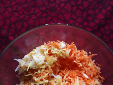 Apfel-Karotten-Salat in Glasschale auf rotem Tischtuch, Karotten - DISF000626
