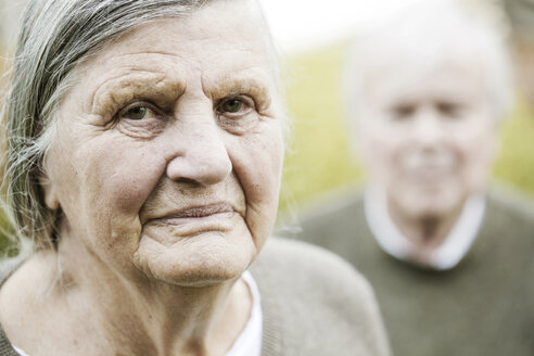 Porträt einer älteren Frau mit Ehemann im Hintergrund - JATF000713