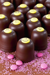 Chocolate marshmallows decorated with different smiley faces, pink sugar and chocolate drops in front - CSF020941
