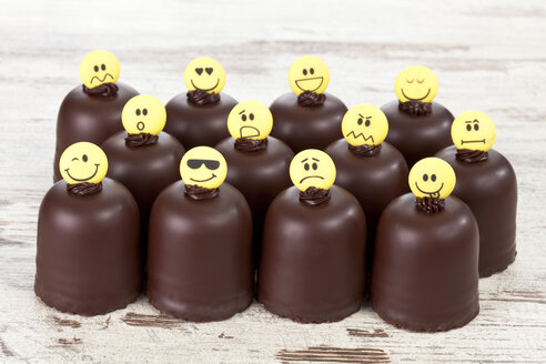 Marshmallows aus Schokolade mit verschiedenen Smiley-Gesichtern auf einem Holztisch - CSF020943