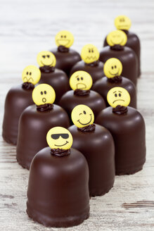 Marshmallows aus Schokolade mit Smiley-Gesichtern auf einem Holztisch - CSF020944