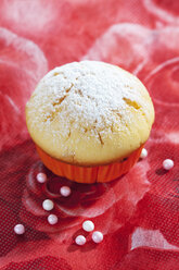 Muffin in Muffinpapier und Zuckerperlen auf rotem Blumenmuster - CSF020970