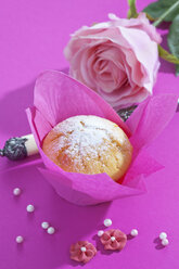 Muffin in rosa Verpackung, Rosenblüte, Tasse und Zuckerperlen auf rosa Grund - CSF020978