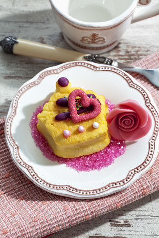 Dekorierte Muffinmarzipanblüte und rosa Zucker auf Teller, lizenzfreies Stockfoto