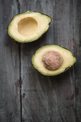 Two halves of an avocado (Persea americana) on wooden tablet - SARF000324