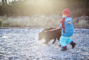 Deutschland, Schleswig-Holstein, Kiel, kleines Mädchen mit Labrador geht am Strand spazieren - JFEF000323