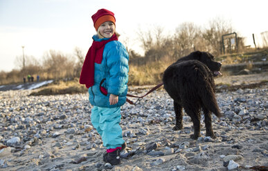 Deutschland, Schleswig-Holstein, Kiel, kleines Mädchen mit Labrador am Strand - JFEF000324