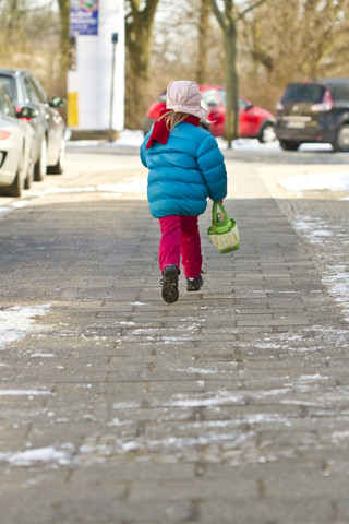 Kleines Mädchen mit Tasche auf dem Bürgersteig, lizenzfreies Stockfoto