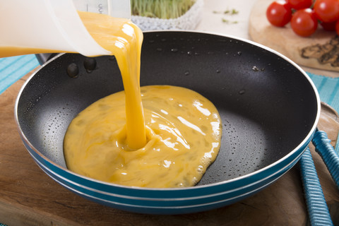 Flüssiges Ei für eine Frittata wird in die Bratpfanne gegossen, lizenzfreies Stockfoto