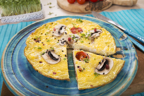 Frittata mit Champignon, Schinkenwürfeln, Tomaten, Sesam und Kresse auf Teller - CSTF000135