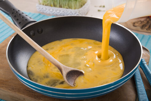 Liquid egg for scrambled eggs is being poured into frying pan - CSTF000136