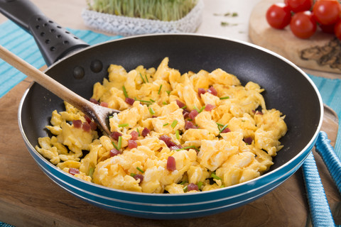 Scrambled eggs with ham cubes in frying pan stock photo