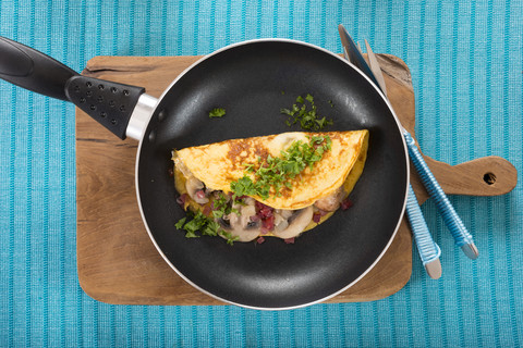 Omelette mit Champignon, Zwiebel und Schinken in der Pfanne, lizenzfreies Stockfoto