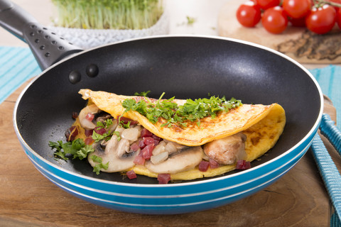 Omelette mit Champignon, Zwiebel und Schinken in der Pfanne, lizenzfreies Stockfoto