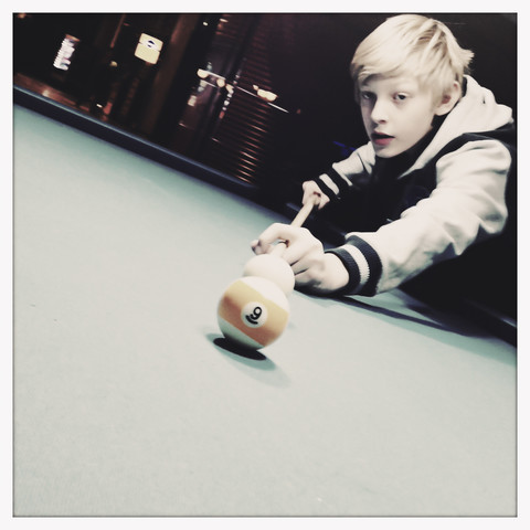 Zwölfjähriger Junge spielt Poolbillard, Hamburg, Deutschland, lizenzfreies Stockfoto