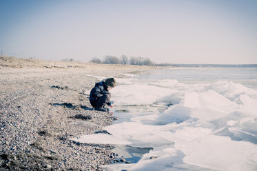 Germany, Mecklenburg-Western Pomerania, Rwegen, little boy playing at waterside in Winter - MJF000884