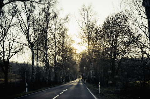 Deutschland, Mecklenburg-Vorpommern, Rügen, leere Landstraße bei Sonnenuntergang im Winter, lizenzfreies Stockfoto