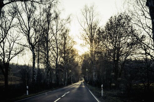 Deutschland, Mecklenburg-Vorpommern, Rügen, leere Landstraße bei Sonnenuntergang im Winter - MJF000905