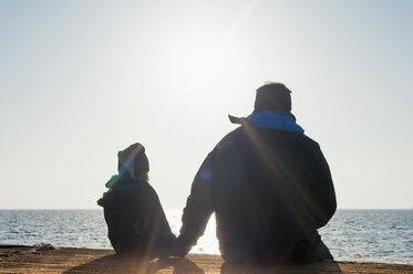 Deutschland, Mecklenburg-Vorpommern, Rügen, Vater und Sohn schauen nebeneinander aufs Meer - MJF000908