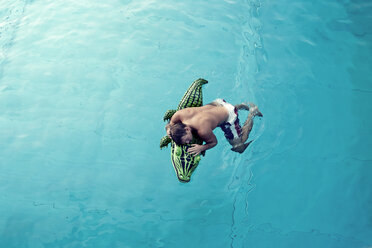 Junger Mann mit Badespielzeug im Wasser schwimmend, Blick von oben - PAF000551