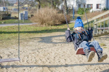 Deutschland, Mecklenburg-Vorpommern, Rügen, kleiner Junge schaukelt auf Spielplatz - MJF000956