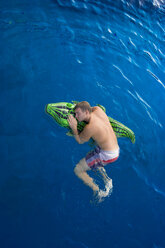 Junger Mann mit Badespielzeug im Wasser schwimmend, Blick von oben - PAF000552