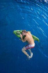 Young man with swim toy floating in water, view from above - PAF000552