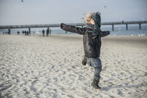 Deutschland, Mecklenburg-Vorpommern, Rügen, kleiner Junge läuft im Winter am Strand - MJF000946