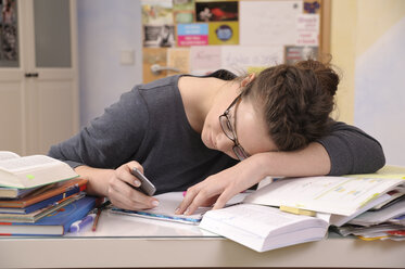 Female pupil with smartphone at her desk - BTF000326