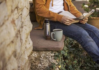 Young man sitting on steps having coffee break, partial view - EBSF000083