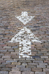 Germany, Bremen, Opposing arrow signs on cobblestone pavement - NKF000067