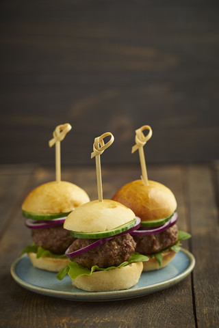 Mini-Burger mit Hackfleisch, Salat und roten Zwiebeln auf Teller, lizenzfreies Stockfoto