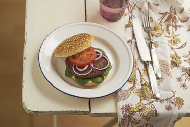 Burger mit Hackfleisch, Tomate, Feldsalat und roten Zwiebeln auf Teller - ECF000450