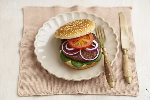 Burger mit Hackfleisch, Tomate, Feldsalat und roten Zwiebeln auf Teller - ECF000462