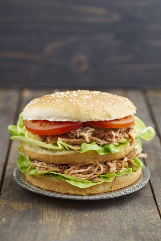 Burger mit Pulled Pork, Tomate und Salat auf Teller, lizenzfreies Stockfoto