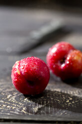 Zwei chinesische Pflaumen (Prunus salicina) auf dunklem Holztisch - MAEF008221