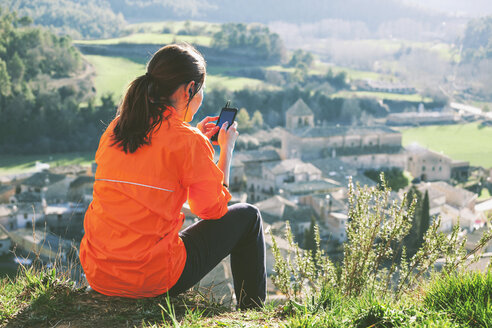 Spanien, Katalonien, Orista, junge Joggerin, die mit ihrem Smartphone eine Pause macht - EBSF000095