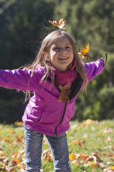Portrait of little girl throwing autumn leaves in park - SARF000365