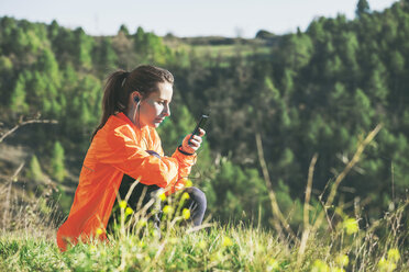 Spanien, Katalonien, Orista, junge Joggerin, die mit ihrem Smartphone eine Pause macht - EBSF000097