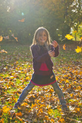 Little girl throwing autumn leaves in park - SARF000368