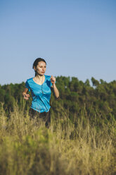 Junge Joggerin in Bewegung vor einem Wald - EBSF000106