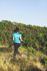 Junge Joggerin in Bewegung vor einem Wald - EBSF000107