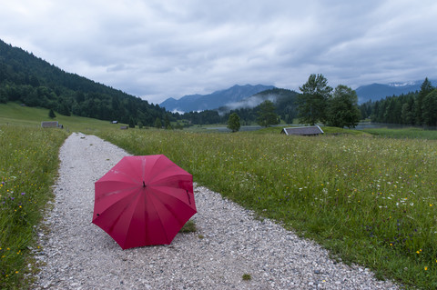Deutschland, Bayern, Werdenfelser Land, Roter offener Regenschirm auf Wanderweg am Geroldsee, lizenzfreies Stockfoto