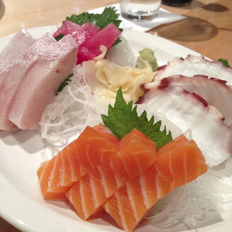 Japanisches Sashimi-Gericht mit rohem Lachs, Thunfisch, Gelbschwanz und Oktopus-Scheiben. - ABAF001274