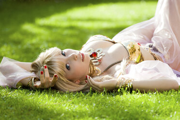 Woman wearing belly dance costume lying in grass - AFF000039